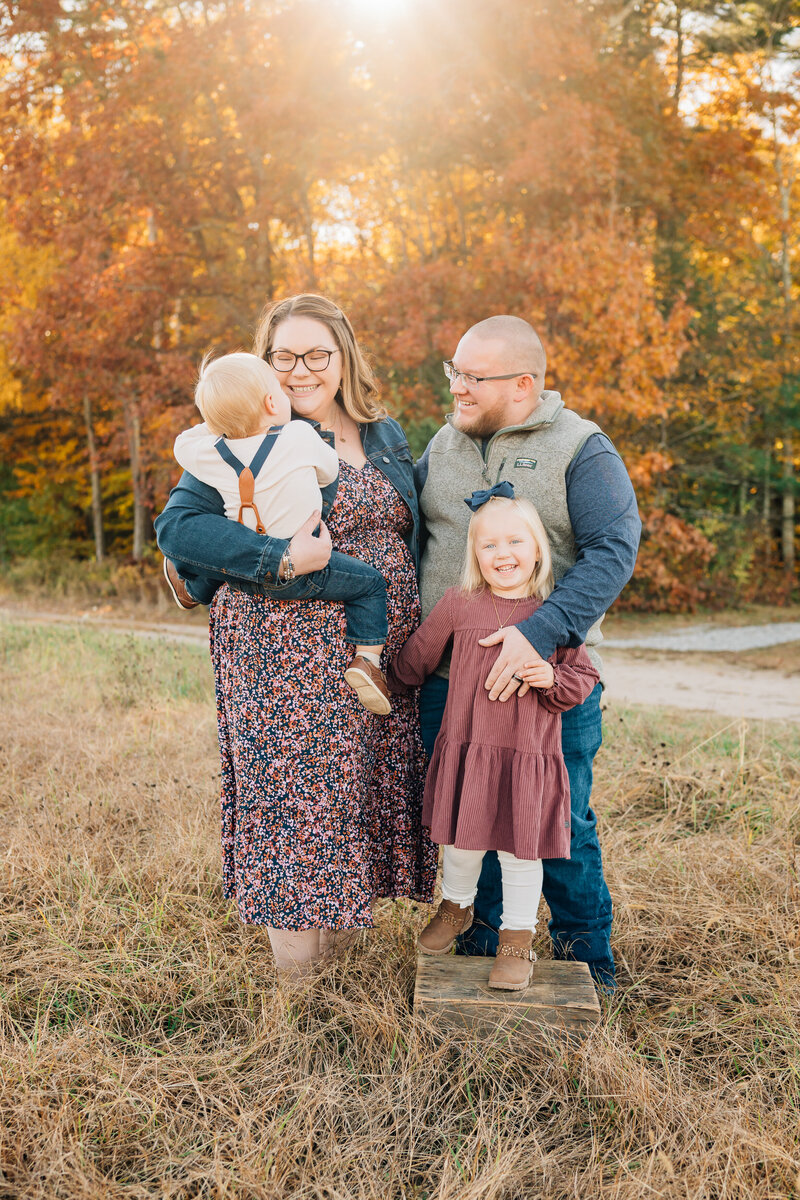 Couple in field, looking down at pregnant mom's belly