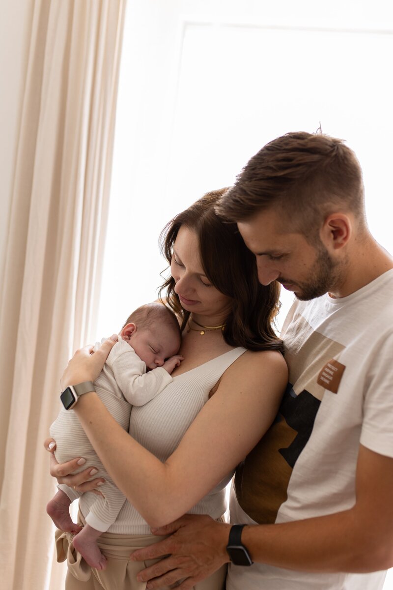 Mutter und Vater stehen dicht an einander und halten Baby