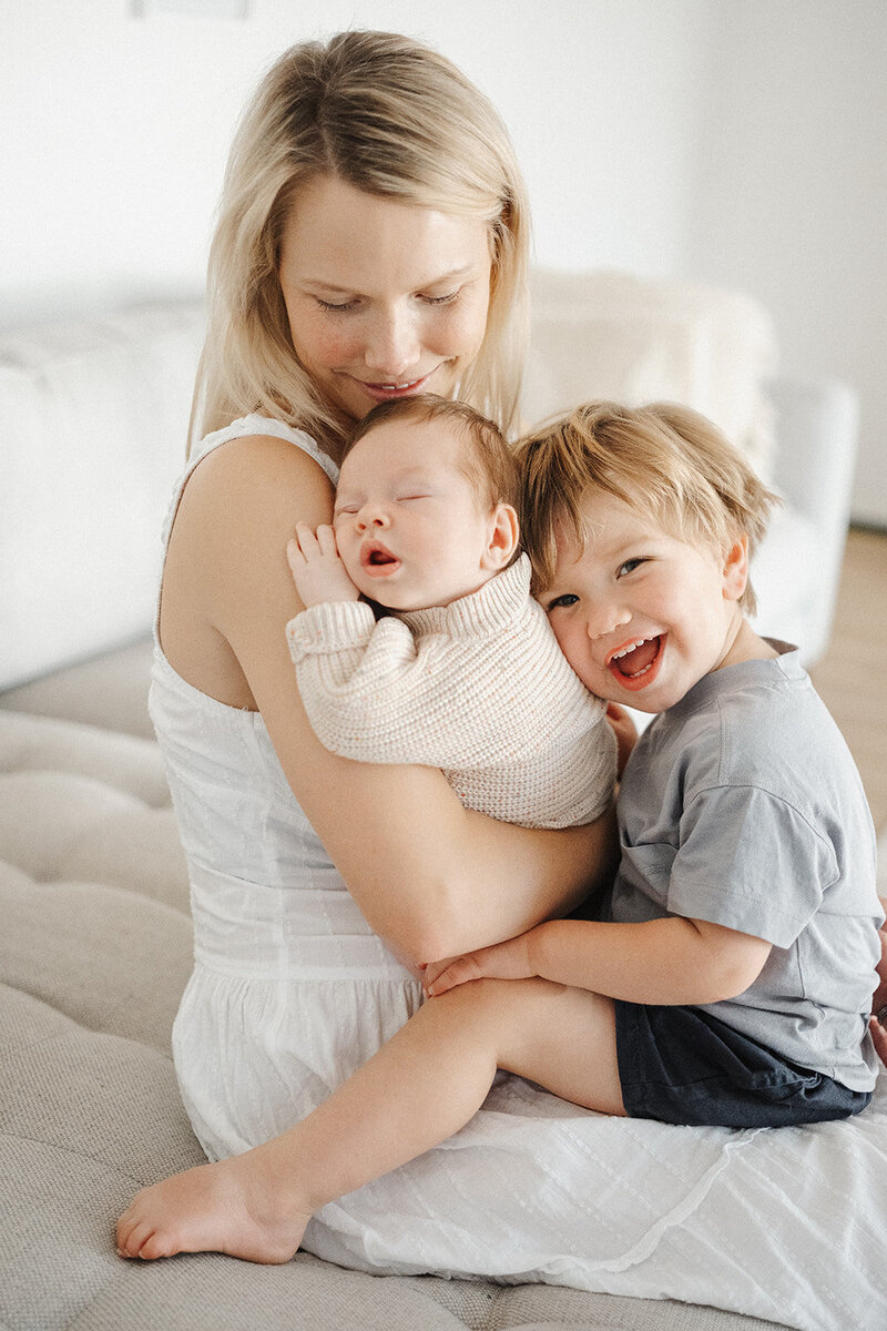 mum holding newborn baby and toddler