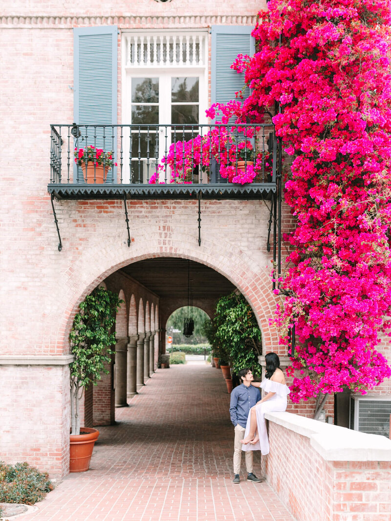 bride and groom engagement session sitting on ledge of brick wall in palos verdes los angeles