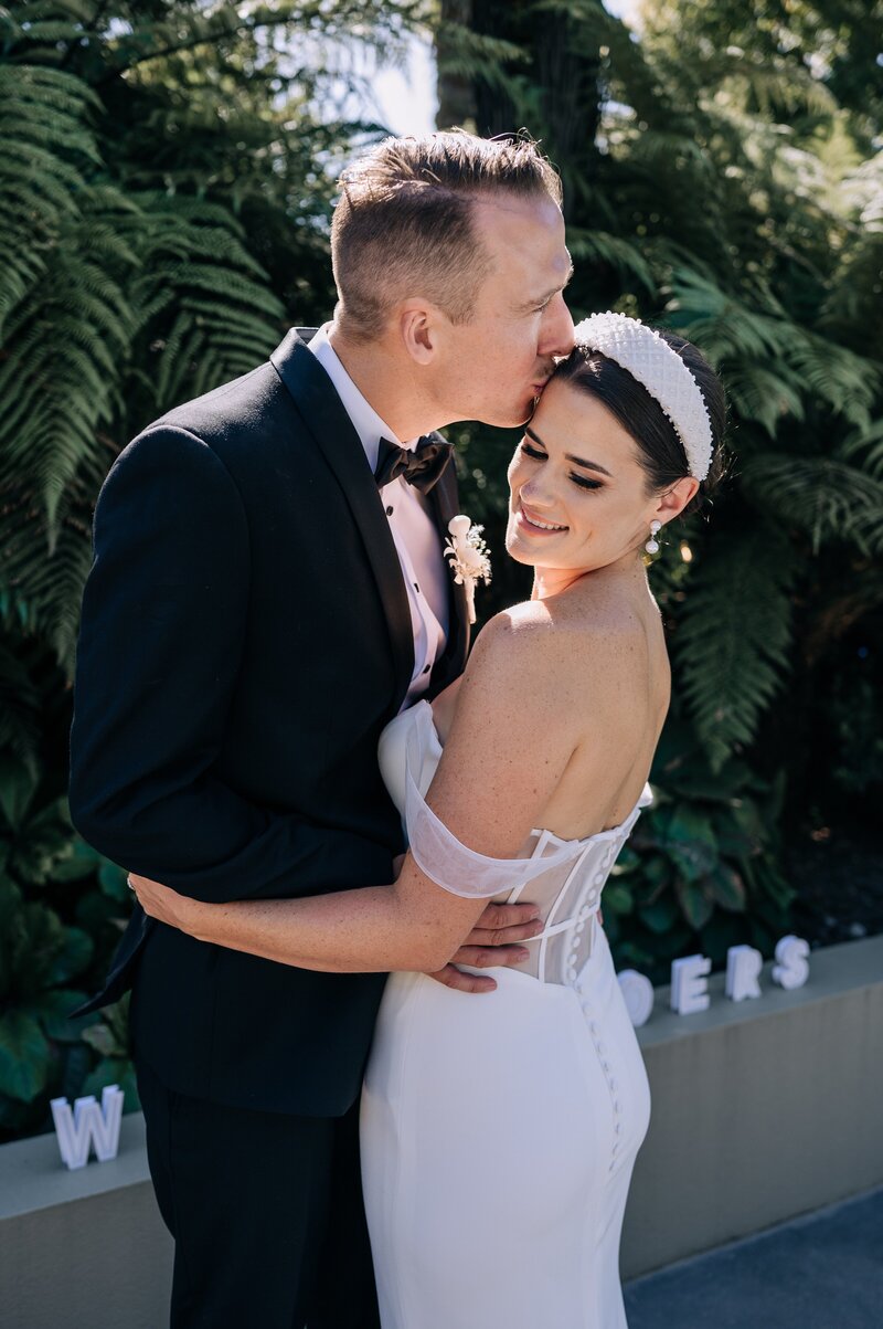 bride in trish peng wedding dress and groom in black tuxedo at their garden party wedding in christchurch