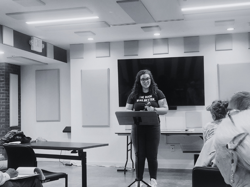 Black and white photo of the owner of a communication and public speaking consulting company speaking to an audience.