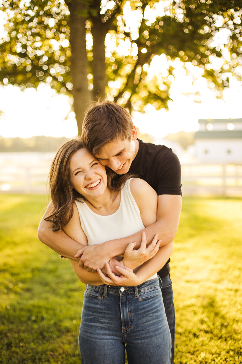 young couple hugging and smiling during outdoor engagement session