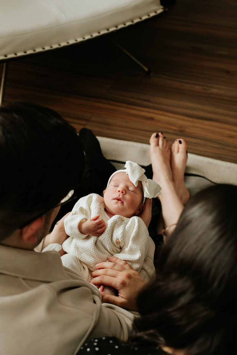 Newborn in white sweater with mom and dad 