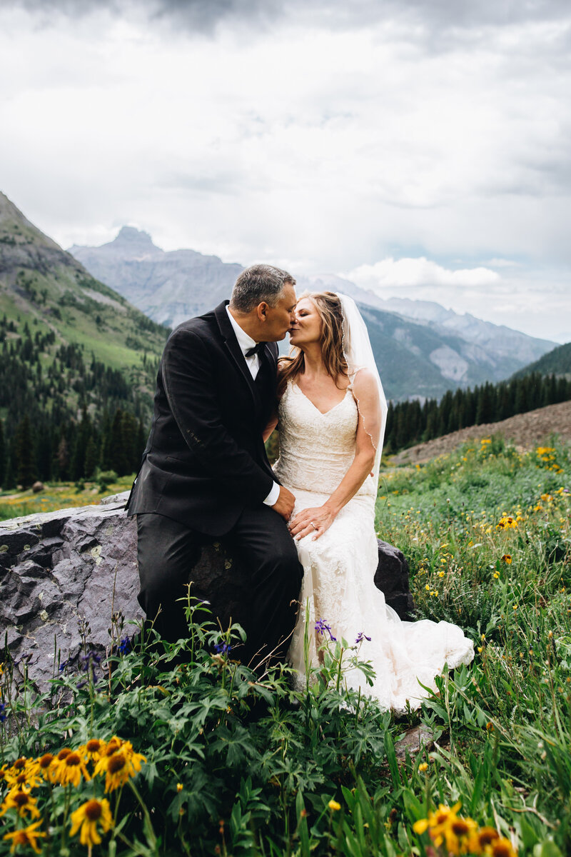 Couple shares a kiss in a field of wildflowers in Ouray, Colorado.