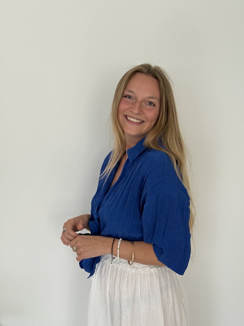Woman with blue shirt and white skirt smiling 