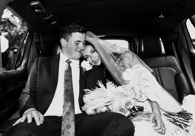 Bride and groom cuddling in a limousine after their church wedding