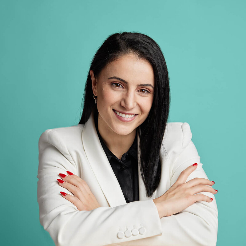 Smiling corporate woman with arms folded against an acqua background.