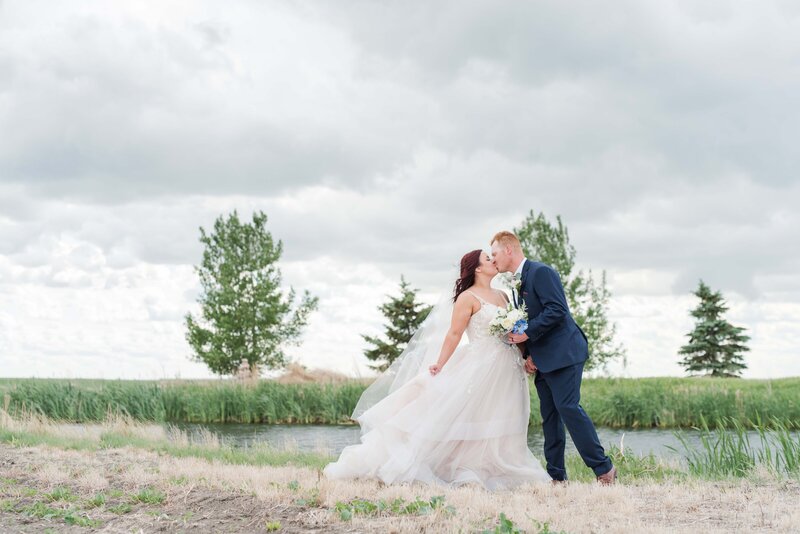 wedding photo of couple standing in front of a grassy pond