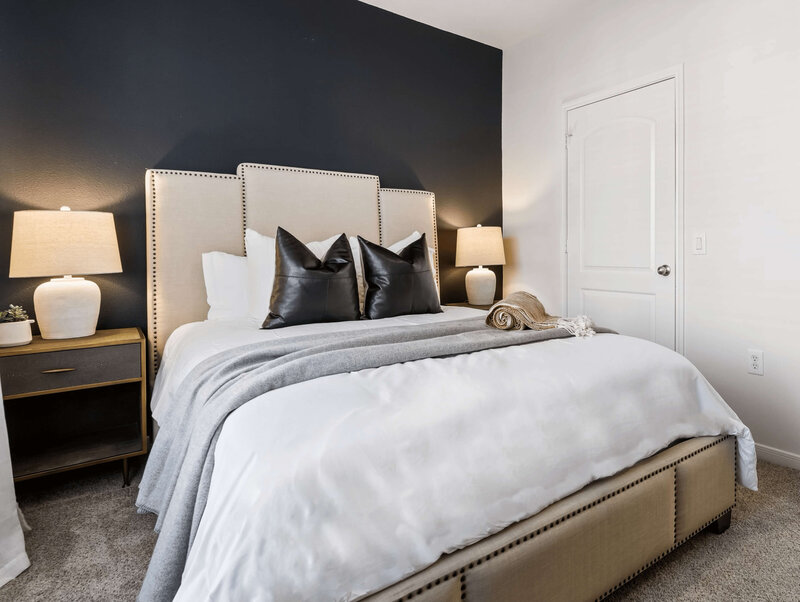 Styled bedroom with dark accent wall and layered bedding