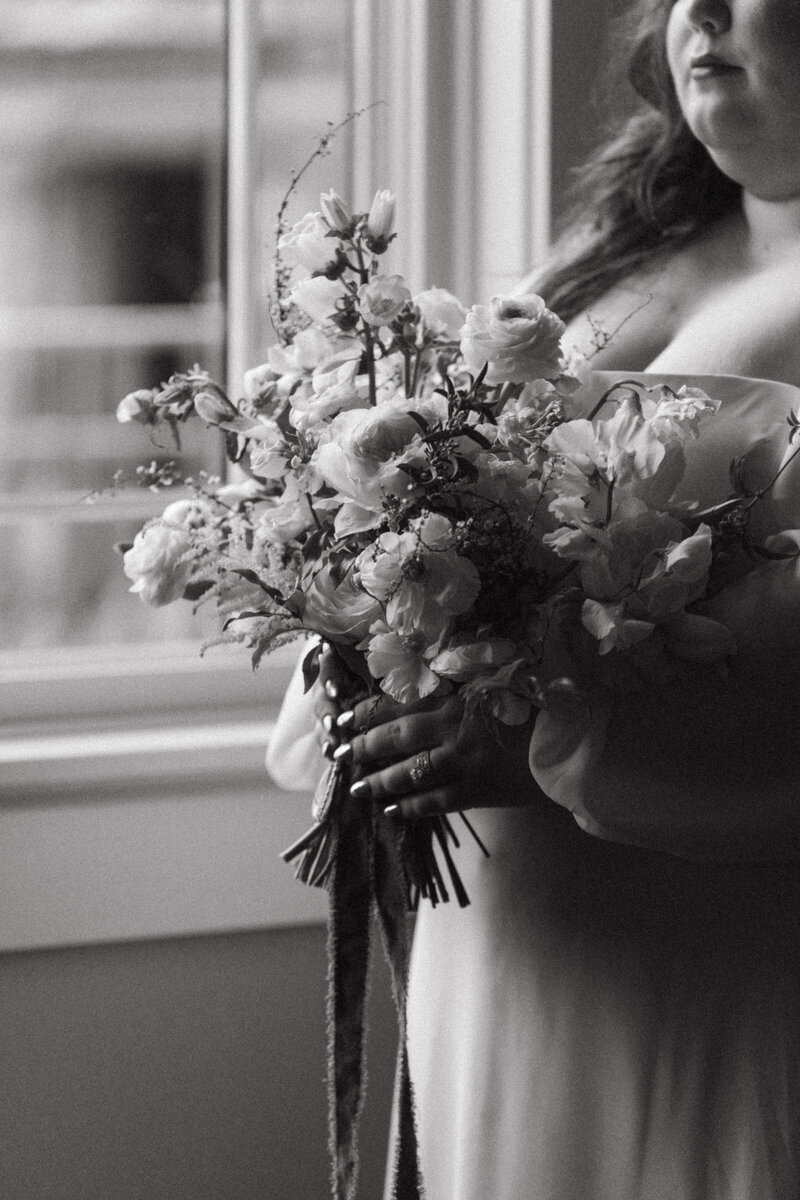 Bride holding pastel bouquet with lace dress details.