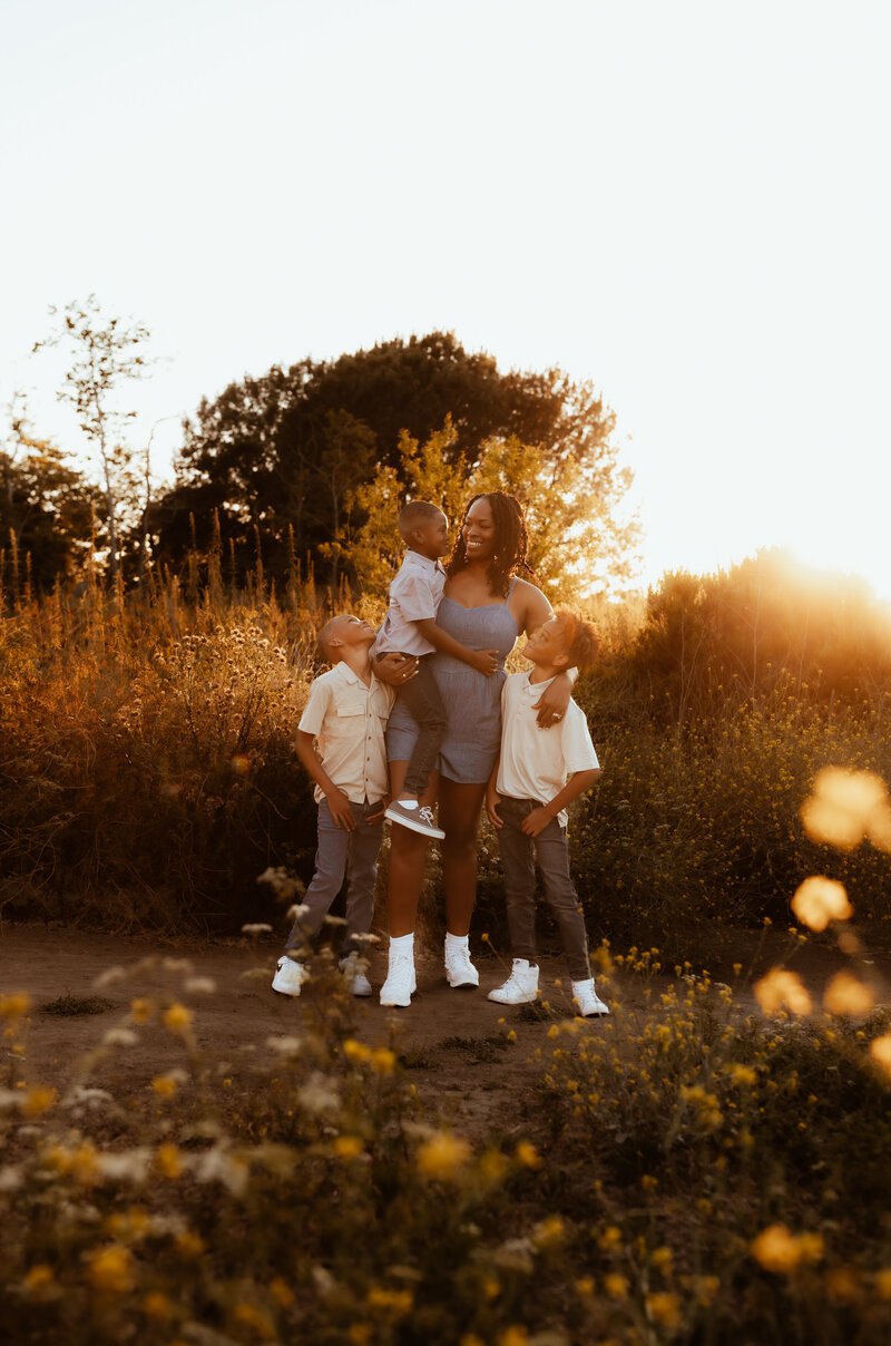 A mother standing with her three boys as the California sun sets behind them. 
