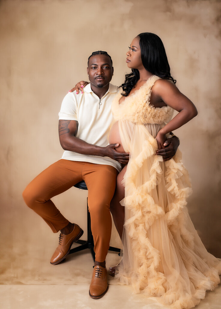 Expecting couple in a soft beige gown and warm-toned outfit during a Bump to Baby maternity photography session in Birmingham, Alabama