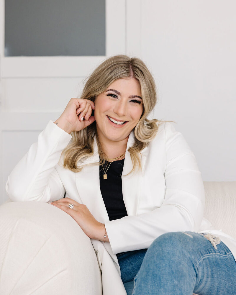Calgary Realtor Leigh Kormos leaning on a white couch