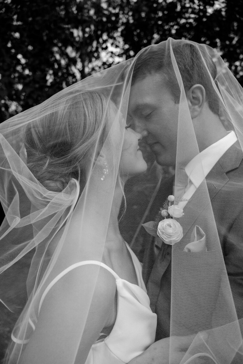 black and white image bride and groom under the veil nose to nose