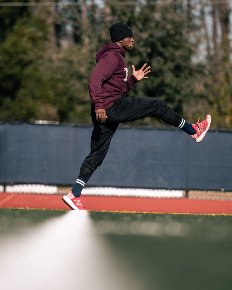 Athlete training doing high-knee drills on a football field