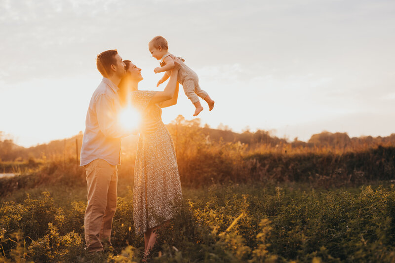 Golden hour family session with parents holding todder in the air