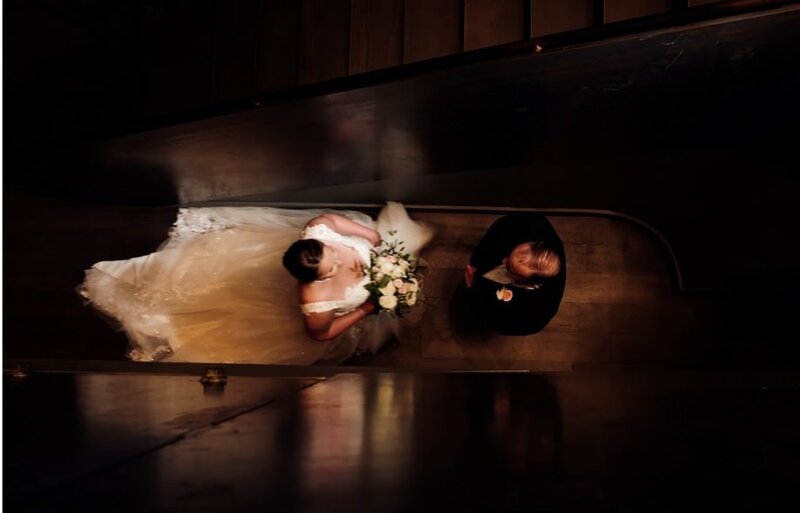 View looking down at a newlywed couple standing in a staircase 