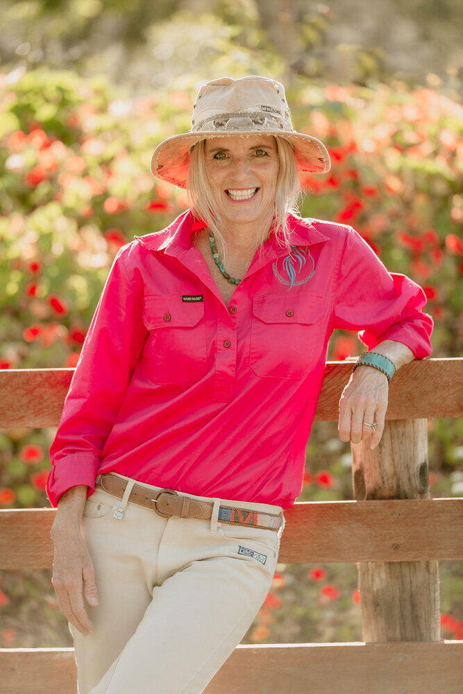 Courtney brown leaning against wooden fence with flowers in the background