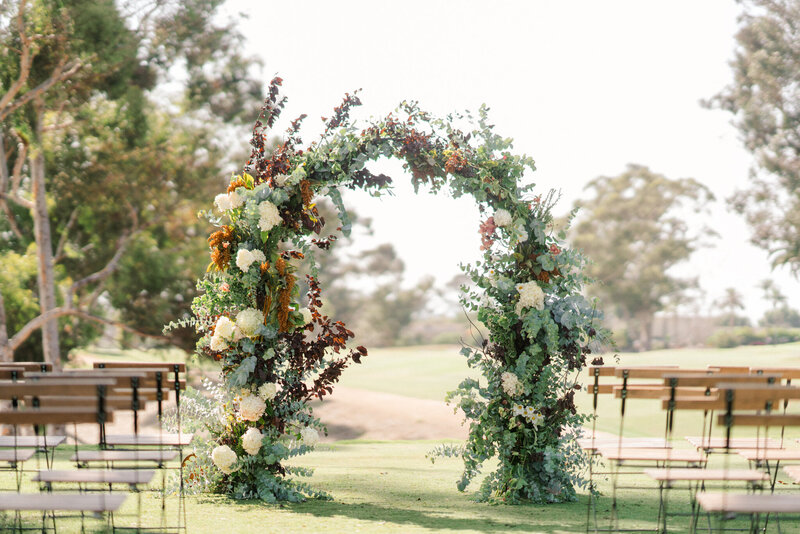 Arch covered in autumn flowers and greenery, designed by Kendra’s Events.