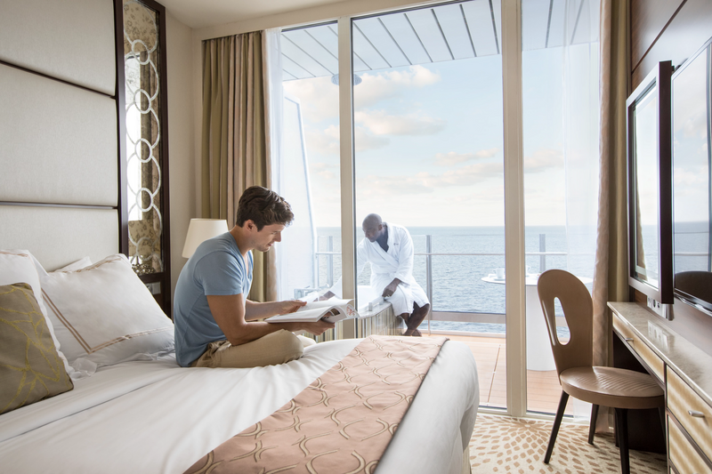 man reading a book on a bed in cruise stateroom