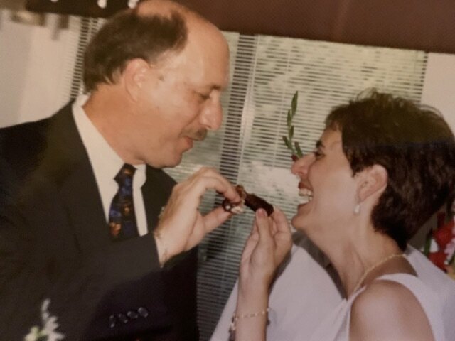 Wedding couple laughing and sharing a taste of their wedding cake