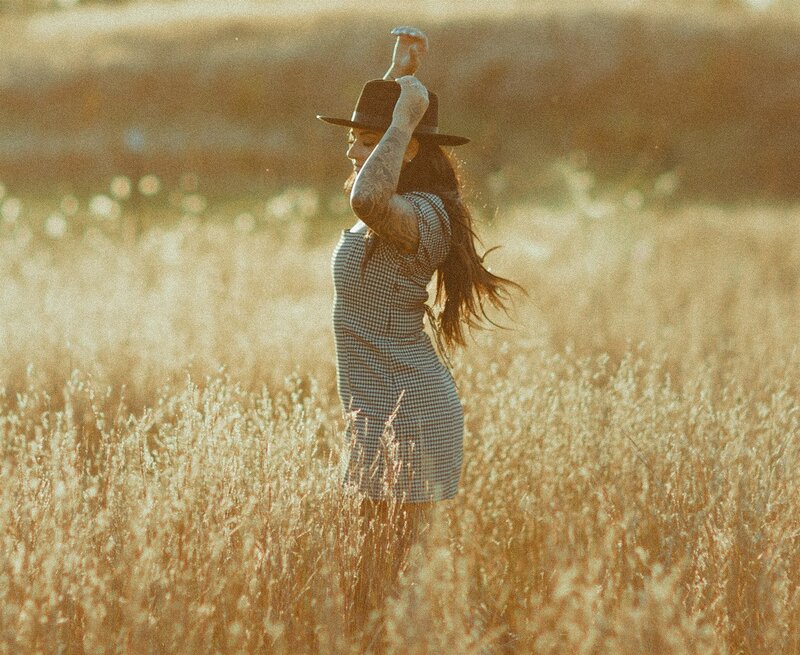 morgan okonek wearing a black hat twirling in a field at sunset