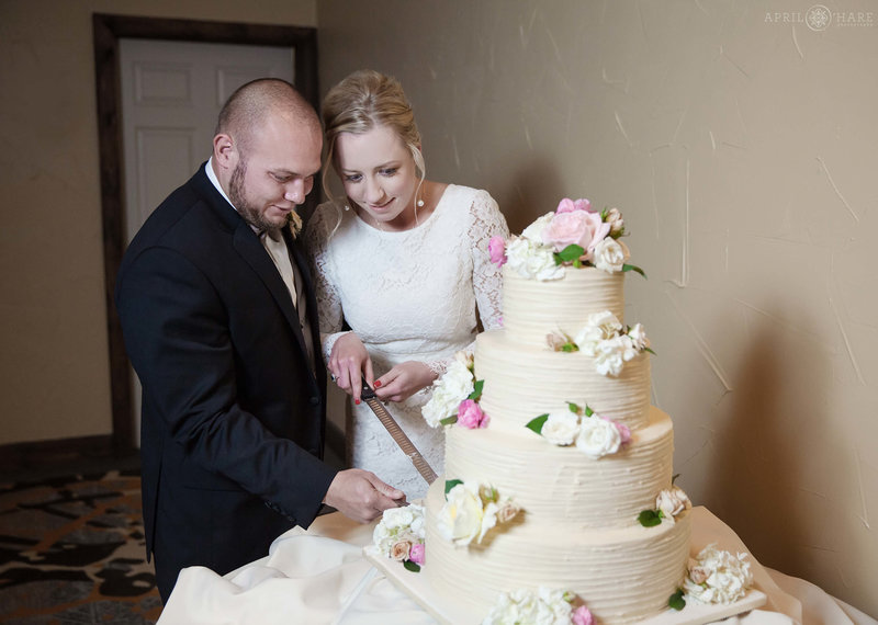 Couple cuts their large 4 tiered wedding cake in the Mountain View Conference Room at their Lodge at Breckenridge Wedding in Colorado