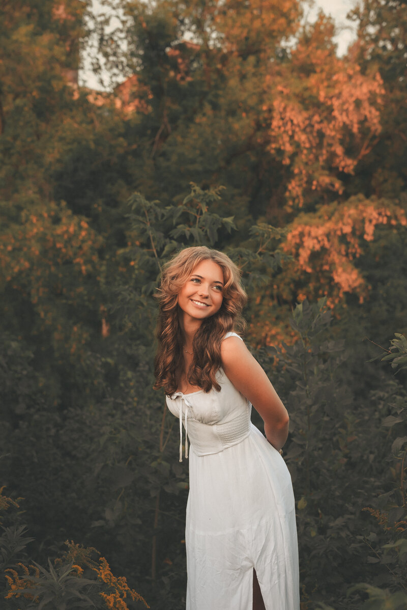 High school senior girl posing in a beautiful outdoor setting at sunset in the Twin Cities, captured by Shannon Kathleen Photography, highlighting her natural beauty and the golden hour glow.