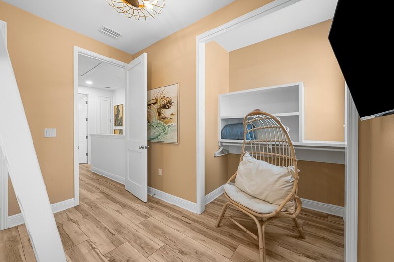 Relaxing bedroom nook with rattan chair and beachy decor at Beach Cabana, a playful and stylish PCB vacation rental near 30A and Destin.