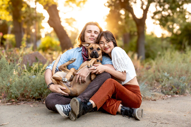 a white man with shoulder length hair and a japanese woman hold their dog for family photos in palo alto at golden hour