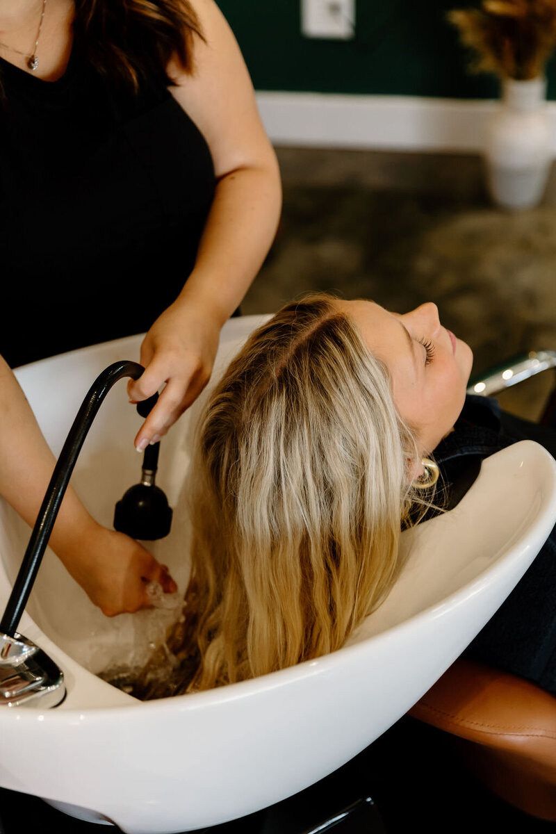 Client receiving professional hair color rinse at The Vanity Hair Studio in Griffin, Georgia, specializing in custom blonding, balayage, and vibrant color treatments.