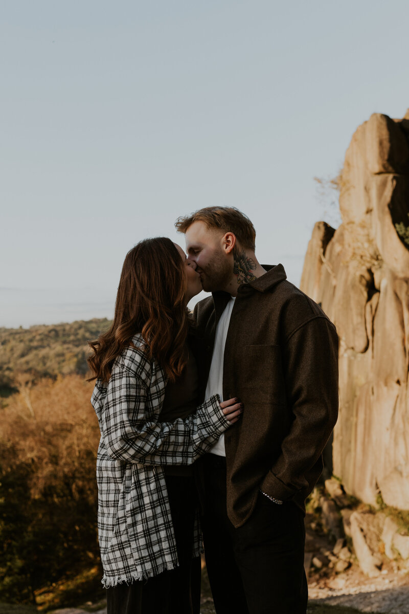 An adventurous couple embraces in the midst of a breathtaking natural landscape, celebrating their engagement