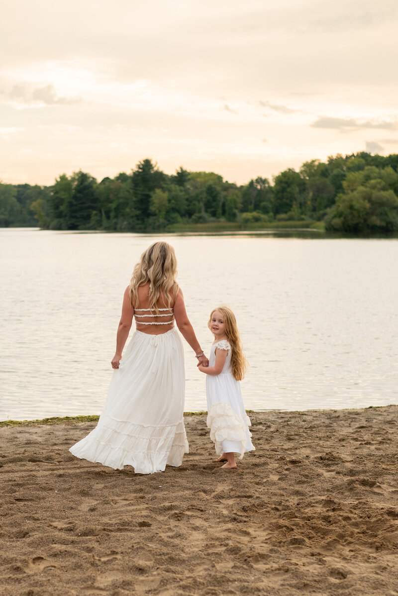 Mother and daughter walking hand in hand towards the beach. 