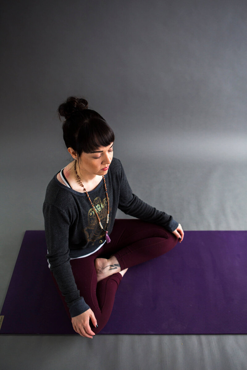 yoga teacher sits cross legged with eyes closed