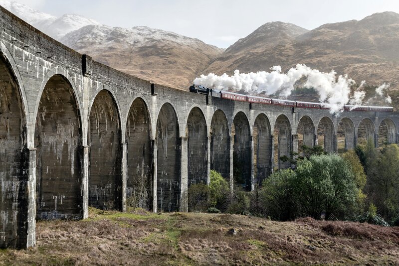 Hogwarts Express train on Glenfinnan Viaduct in the Scottish Highlands, symbolizing a magical literary tour.
