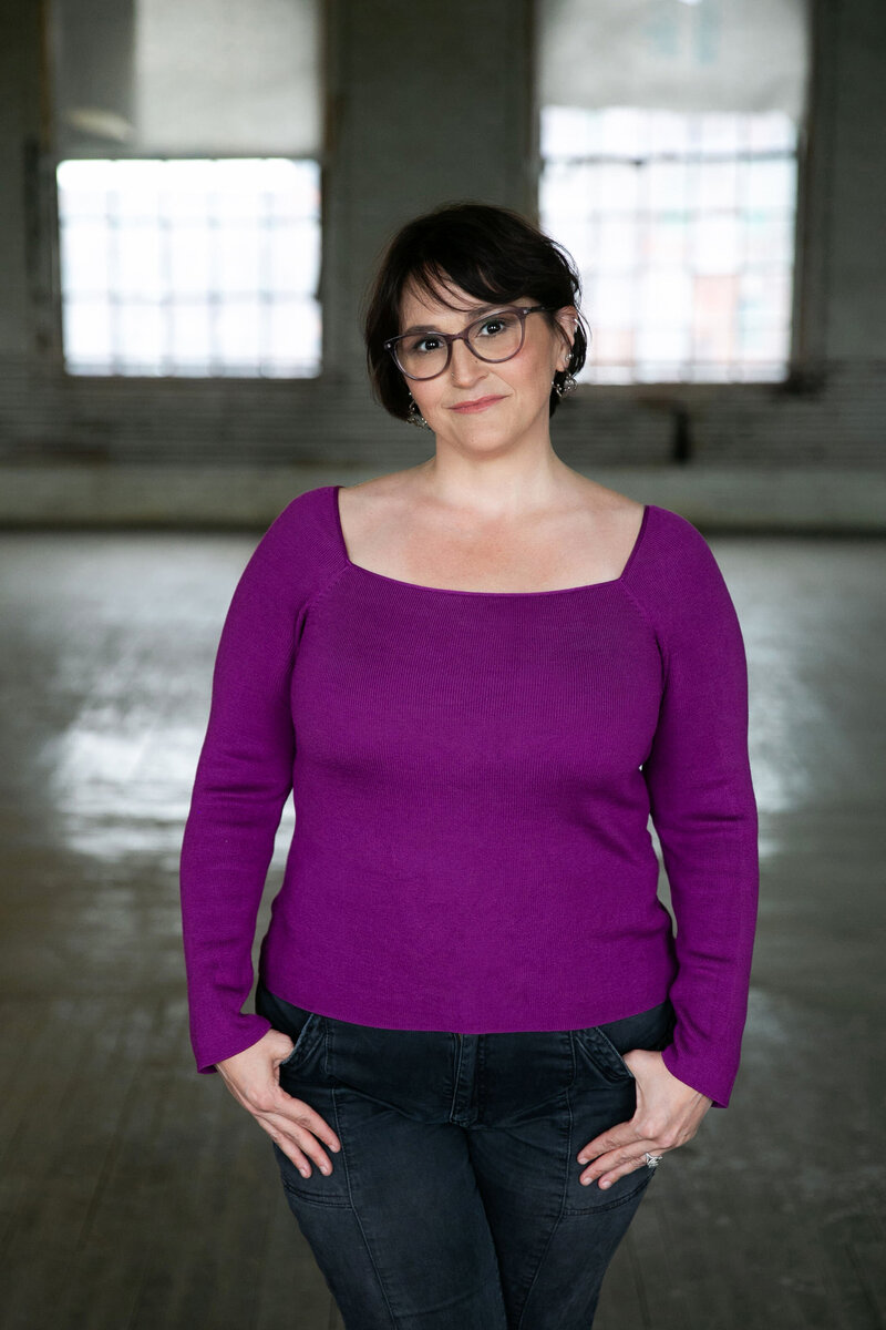 A woman in a purple shirt standing in an empty room