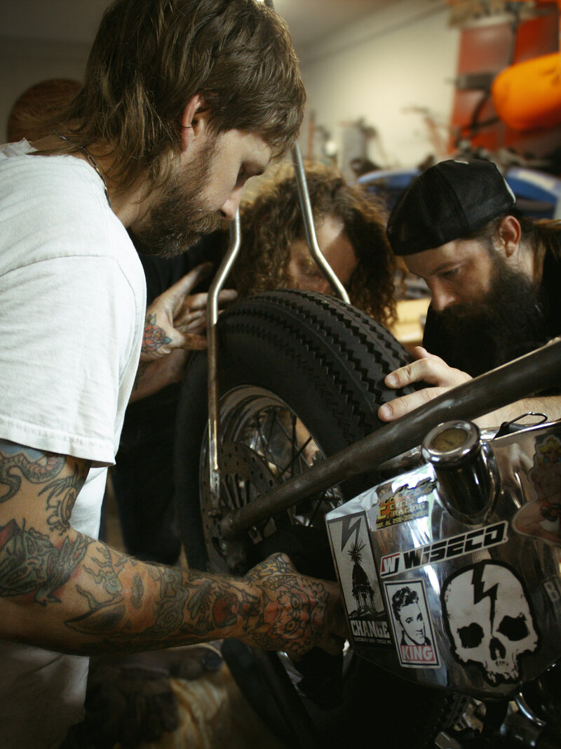 Harley technicians putting the chain on a custom chopper
