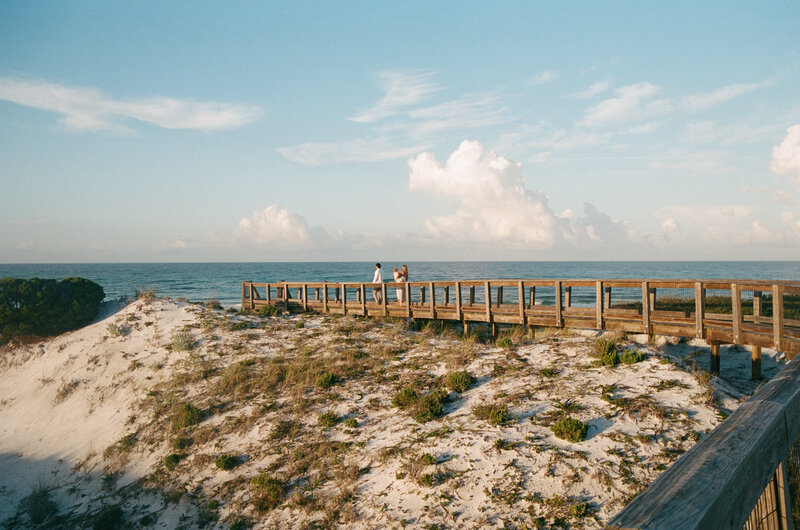 Glowy photo of a family of 4 walking down a boardwalk to the beach 