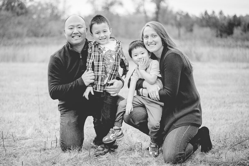 Portland oregon photographer and eugene oregon wedding photographer with her husband and two sons kneeling in field together and smiling