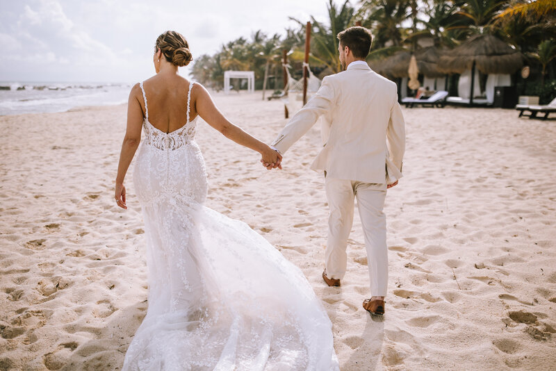 Bride and groom walking on the beach for their destination wedding in Mexico. 