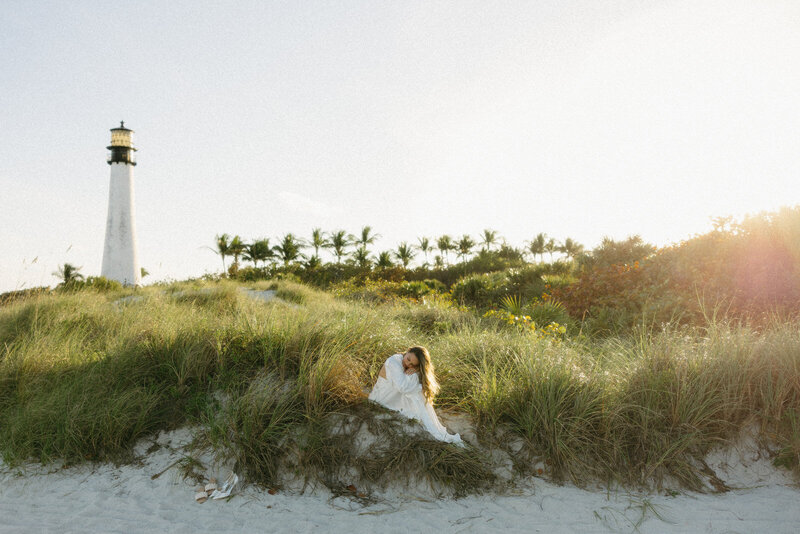 Bride sitting on sand dunes in Miami Florida for her bridal portraits, documented by Andrea-Marie Photography