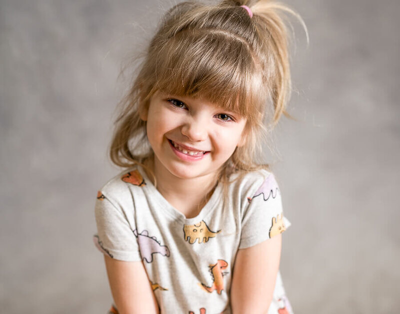 A child smiles with a dino shirt.