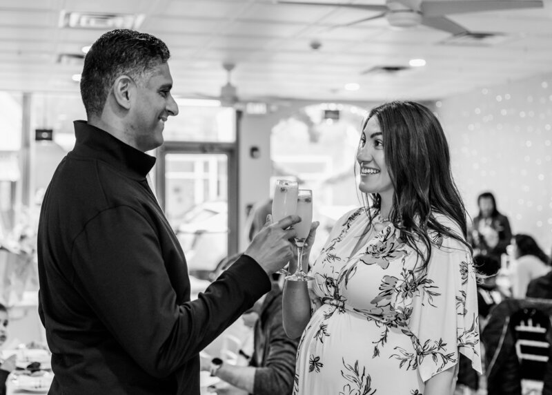 The expecting couple clinks glasses at a toast