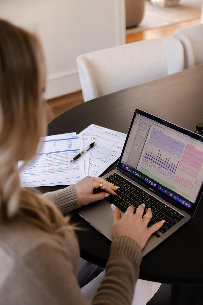 Functional dietician and nutritionist Tracy Greenstein typing client notes on her laptop during a personalized nutrition session