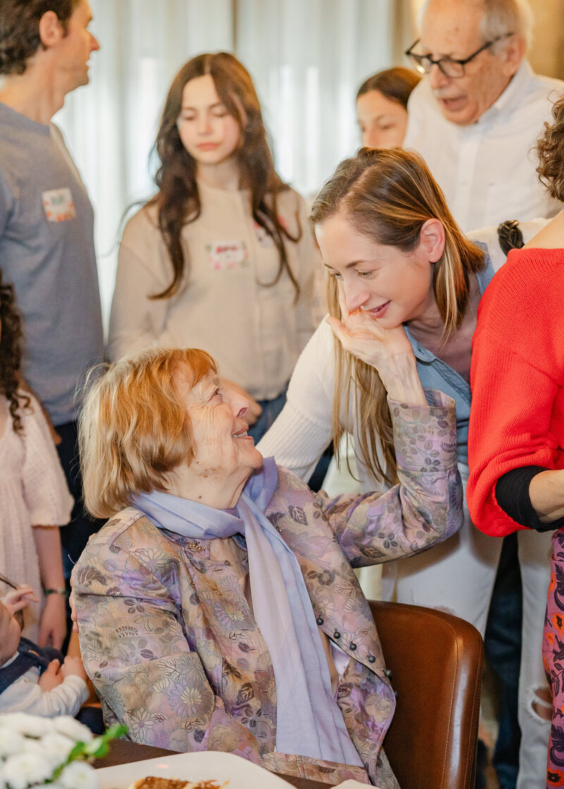A grandmother admires her adult granddaughter at a milestone birthday party.