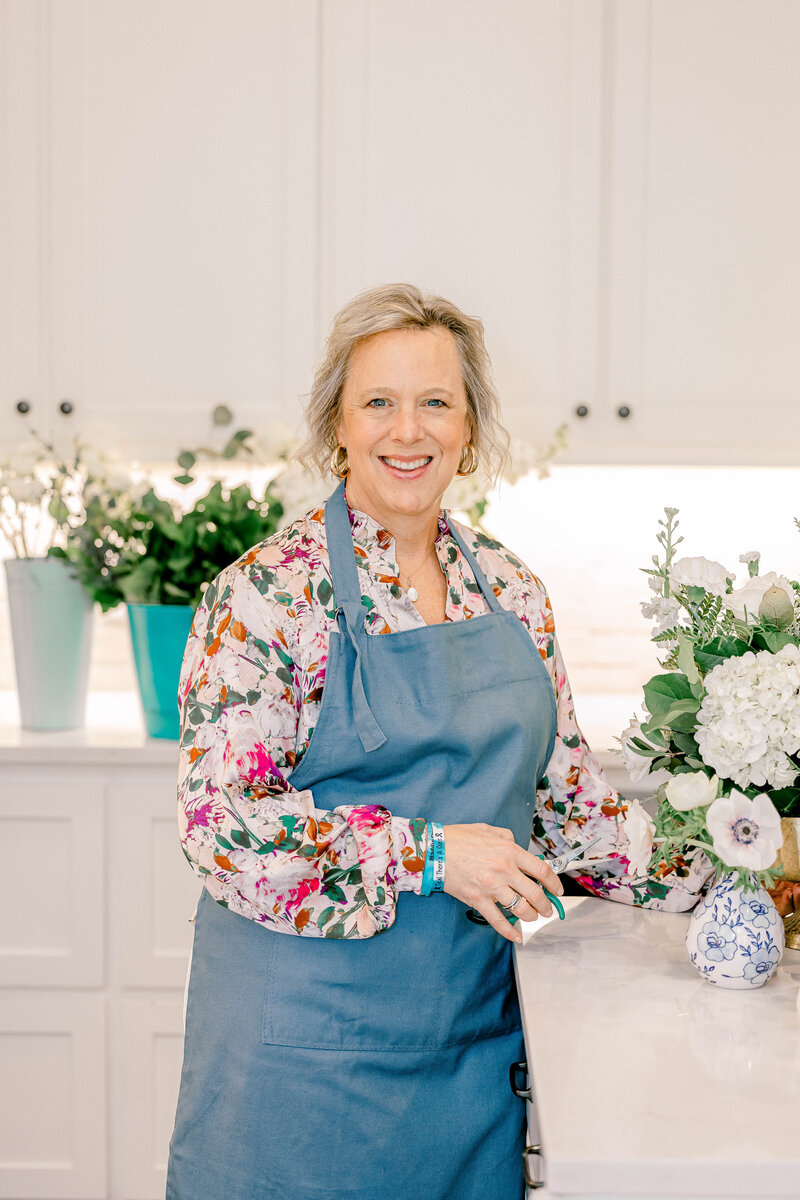 Blonde woman in apron smiling with flowers