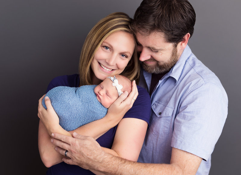 parent pose newborn girl in blue and grey
