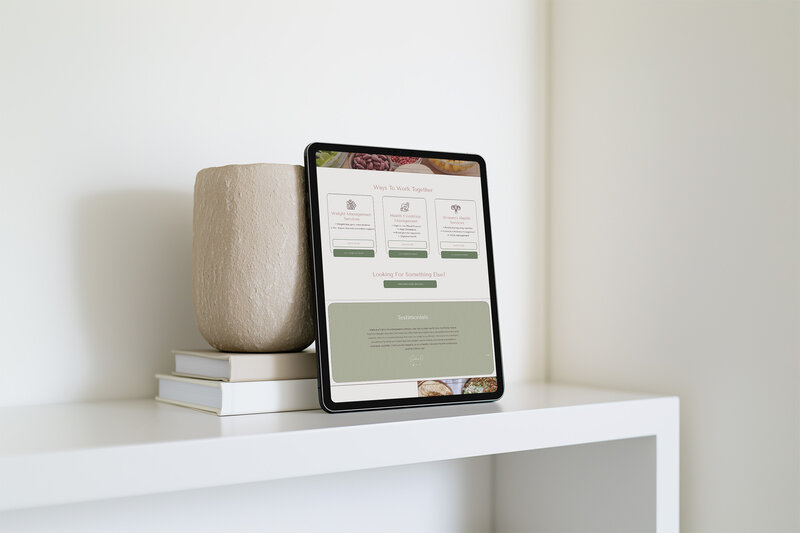 A tablet rests on a shelf, topped with a vase, symbolizing a virtual nutritionist's website design.