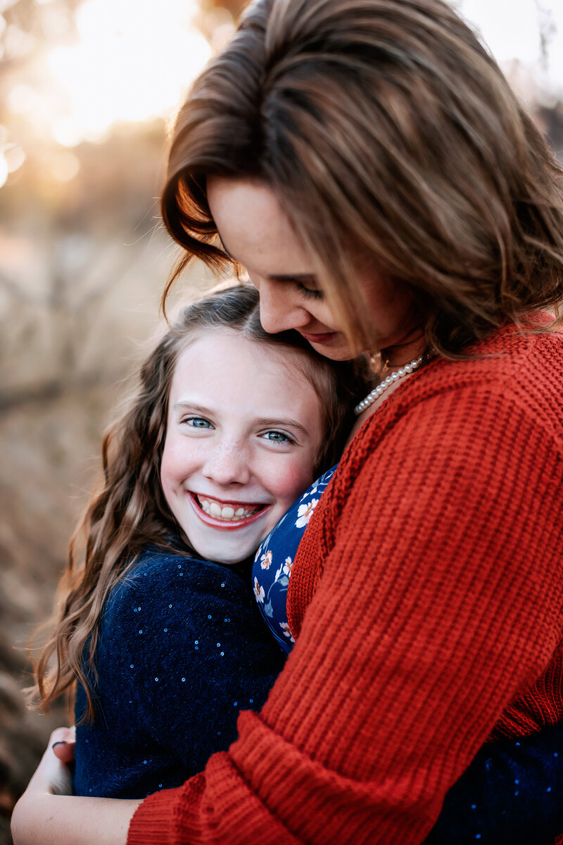 Mother holding her daughter looking down at her while daughter looks at camera at Camplex Park Gillette WY